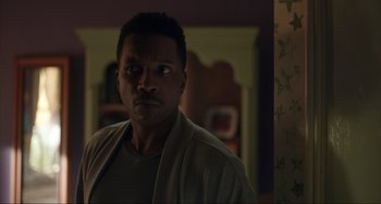 Movie still from “The Exorcist: Believer” (2023), directed by David Gordon Green – A man standing in a living room looking at the camera; Close Up shot, Low angle