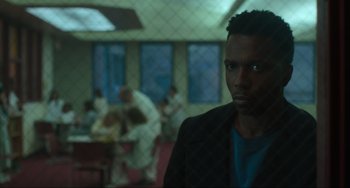 Movie still from “The Exorcist: Believer” (2023), directed by David Gordon Green – A man standing in front of a group of people in a room; Close Up shot, Over the shoulder angle