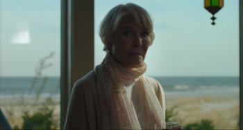 Movie still from “The Exorcist: Believer” (2023), directed by David Gordon Green – An older woman wearing a scarf looking out of a window; Close Up shot, Over the shoulder angle