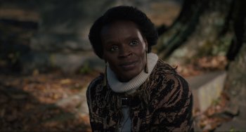 Movie still from “The Exorcist: Believer” (2023), directed by David Gordon Green – A woman in a brown and black jacket is standing in front of a tree; Close Up shot, Over the shoulder angle