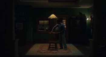 Movie still from “The Exorcist: Believer” (2023), directed by David Gordon Green – A man standing in a room next to a wooden chair; Wide shot, High angle