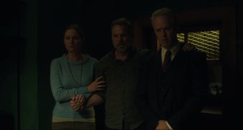 Movie still from “The Exorcist: Believer” (2023), directed by David Gordon Green – A man and two women standing next to each other in a dark room; Medium shot, Low angle