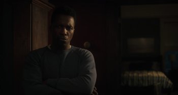 Movie still from “The Exorcist: Believer” (2023), directed by David Gordon Green – A man standing in the dark with his arms crossed; Close Up shot, Over the shoulder angle