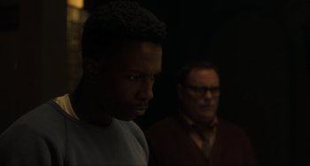 Movie still from “The Exorcist: Believer” (2023), directed by David Gordon Green – A man standing next to another man in a dark room; Close Up shot, Over the shoulder angle