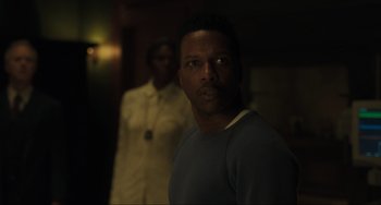 Movie still from “The Exorcist: Believer” (2023), directed by David Gordon Green – A man standing next to another man in a dark room; Close Up shot, Over the shoulder angle