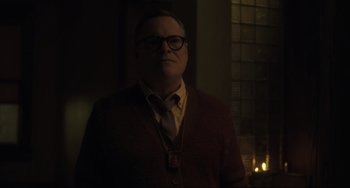 Movie still from “The Exorcist: Believer” (2023), directed by David Gordon Green – A man wearing glasses and a sweater standing next to a candle; Close Up shot, Over the shoulder angle