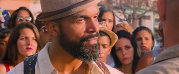 Movie still from “The Fate of the Furious” (2017), directed by F. Gary Gray – A man with a beard and a hat is looking at the camera; Close Up shot, Over the shoulder angle