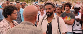 Movie still from “The Fate of the Furious” (2017), directed by F. Gary Gray – A man with a beard talking to another man in front of a group of people; Close Up shot, Over the shoulder angle