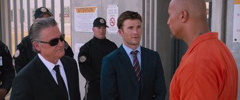 Movie still from “The Fate of the Furious” (2017), directed by F. Gary Gray – A man in a suit and tie standing next to a man in a suit and tie; Medium shot, Over the shoulder angle