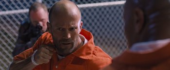 Movie still from “The Fate of the Furious” (2017), directed by F. Gary Gray – A bald man in an orange jacket is looking at the camera; Close Up shot, Over the shoulder angle