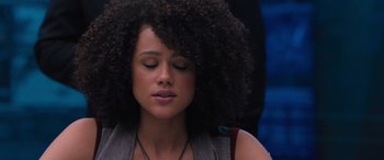 Movie still from “The Fate of the Furious” (2017), directed by F. Gary Gray – A beautiful young woman with a curly afro sitting in front of a blue wall; Close Up shot, High angle