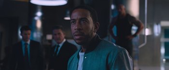 Movie still from “The Fate of the Furious” (2017), directed by F. Gary Gray – A person wearing a suit and tie; Close Up shot, Over the shoulder angle