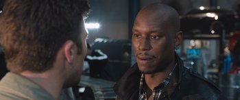 Movie still from “The Fate of the Furious” (2017), directed by F. Gary Gray – A man in a plaid shirt talking to another man in a brown jacket; Close Up shot, Over the shoulder angle