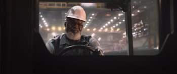 Movie still from “The Fate of the Furious” (2017), directed by F. Gary Gray – An older man wearing a white hard hat driving a truck; Close Up shot, Low angle