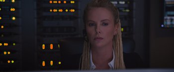 Movie still from “The Fate of the Furious” (2017), directed by F. Gary Gray – A woman with blonde dreadlocks sitting at a computer desk; Close Up shot, Low angle