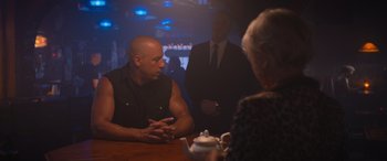 Movie still from “The Fate of the Furious” (2017), directed by F. Gary Gray – Two men and a woman are sitting at a table; Medium shot, Over the shoulder angle