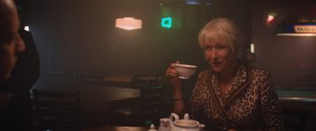 Movie still from “The Fate of the Furious” (2017), directed by F. Gary Gray – A woman sitting at a table holding a tea cup; Medium shot, Low angle
