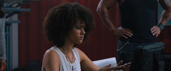 Movie still from “The Fate of the Furious” (2017), directed by F. Gary Gray – A young woman with afro hair looking at a cell phone; Close Up shot, Over the shoulder angle