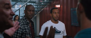 Movie still from “The Fate of the Furious” (2017), directed by F. Gary Gray – Two men standing next to each other in front of a staircase; Medium shot, Over the shoulder angle