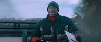 Movie still from “The Fate of the Furious” (2017), directed by F. Gary Gray – A man sitting on top of a bench holding a skateboard; Medium shot, Low angle