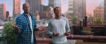 Movie still from “The Fate of the Furious” (2017), directed by F. Gary Gray – A man standing in front of a window with a city in the background; Medium shot, Over the shoulder angle