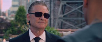 Movie still from “The Fate of the Furious” (2017), directed by F. Gary Gray – An older man wearing sunglasses and a suit; Close Up shot, Low angle