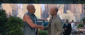 Movie still from “The Fate of the Furious” (2017), directed by F. Gary Gray – Two men shaking hands in front of a city; Medium shot, Over the shoulder angle