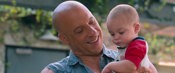 Movie still from “The Fate of the Furious” (2017), directed by F. Gary Gray – A bald man holding a small child in his arms; Close Up shot, Over the shoulder angle
