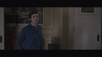 Movie still from “The Father” (2020), directed by Florian Zeller – A person standing in a room with a painting on the wall behind them; Medium shot, Over the shoulder angle