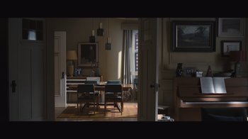 Movie still from “The Father” (2020), directed by Florian Zeller – A dining room with a table and chairs and a piano; Extreme Wide shot, High angle