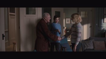 Movie still from “The Father” (2020), directed by Florian Zeller – Two women and an old man shaking hands in a room; Medium shot, Over the shoulder angle