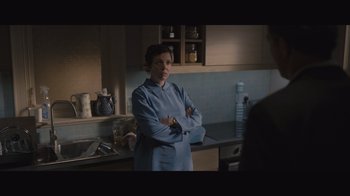Movie still from “The Father” (2020), directed by Florian Zeller – A woman standing in a kitchen with her arms crossed; Medium shot, Over the shoulder angle