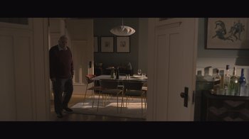 Movie still from “The Father” (2020), directed by Florian Zeller – An older man standing in front of a dining room table; Wide shot, High angle