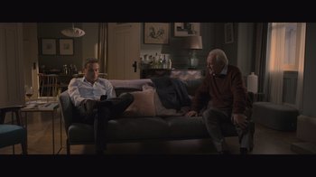 Movie still from “The Father” (2020), directed by Florian Zeller – Two people sitting on a couch in a living room; Wide shot, High angle