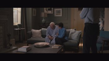 Movie still from “The Father” (2020), directed by Florian Zeller – A man and a woman sitting on a couch in a living room; Wide shot, High angle