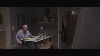 Movie still from “The Father” (2020), directed by Florian Zeller – An older man sitting at a table in a room; Wide shot, High angle