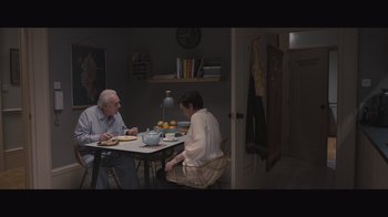 Movie still from “The Father” (2020), directed by Florian Zeller – Two people sitting at a table with a basket; Wide shot, High angle