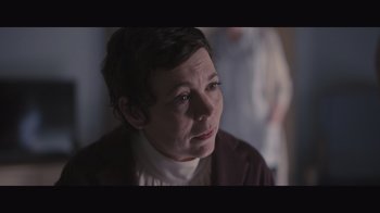 Movie still from “The Father” (2020), directed by Florian Zeller – A woman with short black hair is sitting in a dark room; Close Up shot, Over the shoulder angle