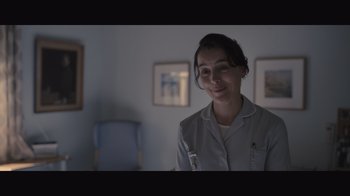 Movie still from “The Father” (2020), directed by Florian Zeller – A woman is smiling in a room with pictures on the wall; Close Up shot, Low angle