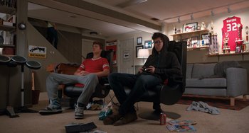 Movie still from “The Fault in Our Stars” (2014), directed by Josh Boone – Two young men sitting in a living room playing a video game; Wide shot, High angle
