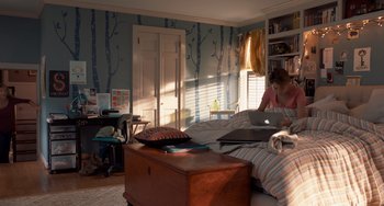 Movie still from “The Fault in Our Stars” (2014), directed by Josh Boone – A woman sitting on top of a bed using a laptop computer; Wide shot, High angle