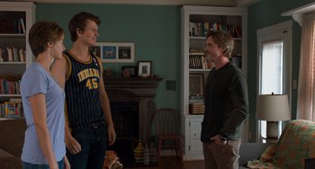 Movie still from “The Fault in Our Stars” (2014), directed by Josh Boone – Two young men standing next to each other in a living room; Medium shot, Over the shoulder angle