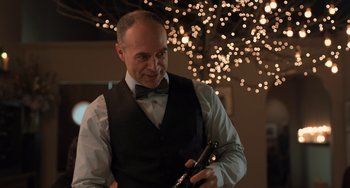 Movie still from “The Fault in Our Stars” (2014), directed by Josh Boone – A man in a vest and bow tie holding a flute; Close Up shot, Over the shoulder angle
