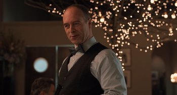 Movie still from “The Fault in Our Stars” (2014), directed by Josh Boone – A man wearing a vest and a bow tie in front of lights; Close Up shot, Over the shoulder angle