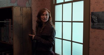 Movie still from “The Fault in Our Stars” (2014), directed by Josh Boone – A woman leaning against a wall in front of a window; Medium shot, Over the shoulder angle