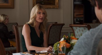 Movie still from “The Fault in Our Stars” (2014), directed by Josh Boone – A woman sitting at a table with a vase of flowers in front of her; Medium shot, Over the shoulder angle