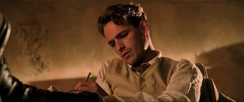 Movie still from “The Fifth Element” (1997), directed by Luc Besson – A man sitting down while holding a cigarette in his mouth; Close Up shot, Low angle