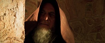 Movie still from “The Fifth Element” (1997), directed by Luc Besson – An old man with a long beard wearing a hooded robe; Close Up shot, Low angle