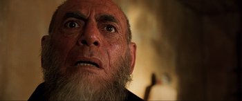 Movie still from “The Fifth Element” (1997), directed by Luc Besson – An old man with a beard looking up at the camera; Close Up shot, Low angle