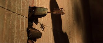 Movie still from “The Fifth Element” (1997), directed by Luc Besson – A person standing on a wooden floor holding a stick; Extreme Close Up shot, Overhead angle